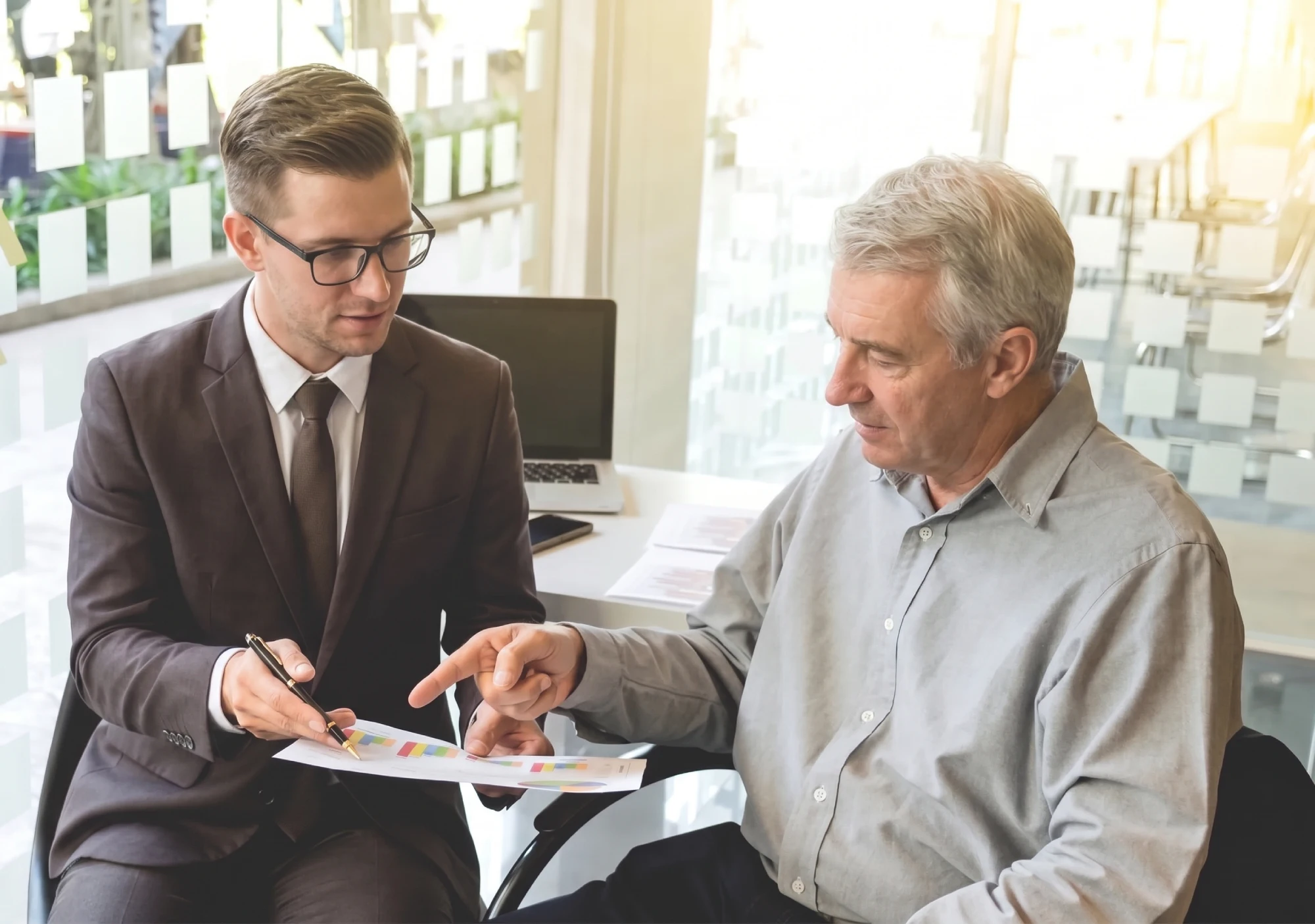 Two men discussing documents in an office setting