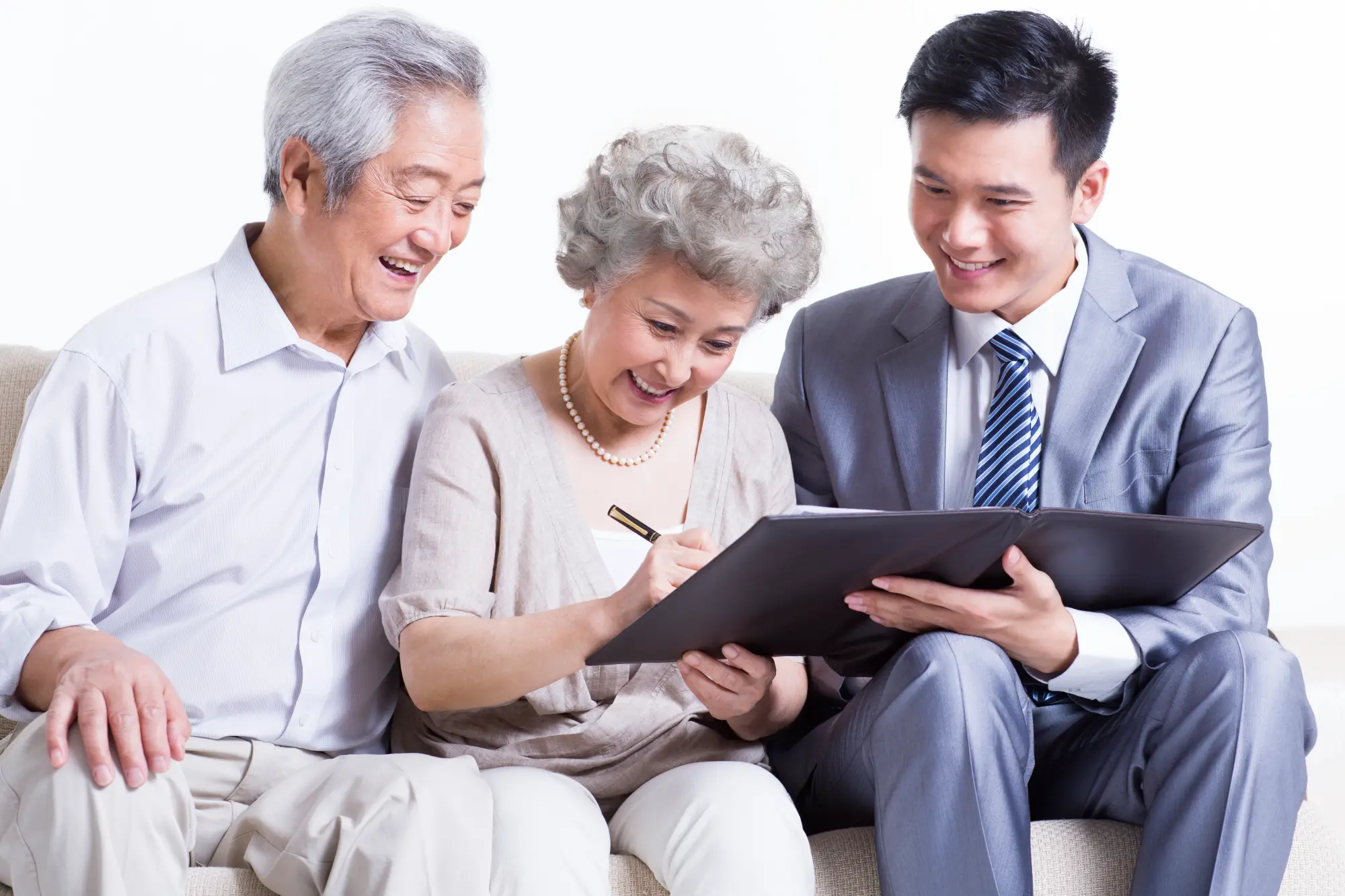 Two seniors and a young man smiling while looking at a document.