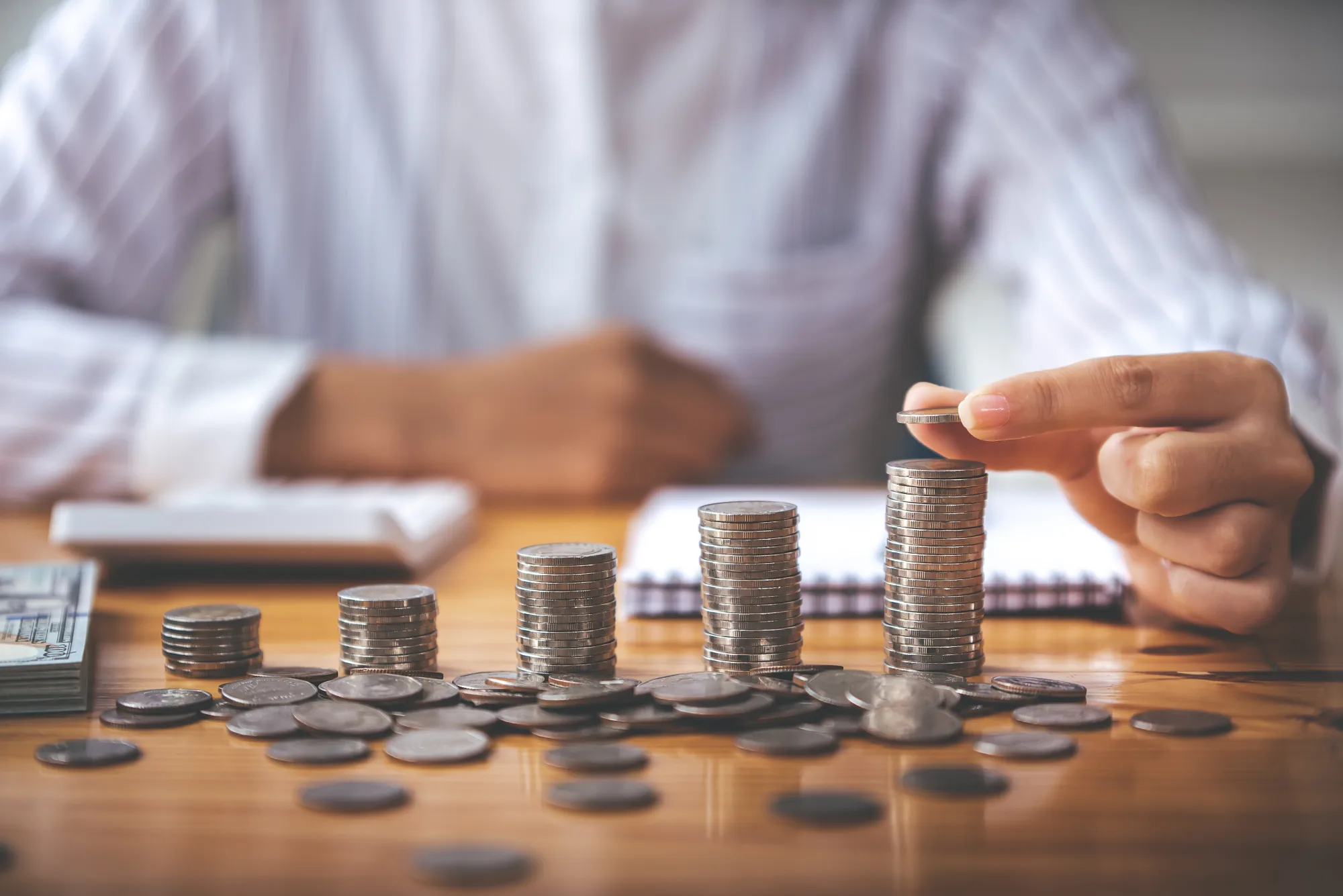 Person stacking coins, representing financial growth and savings.